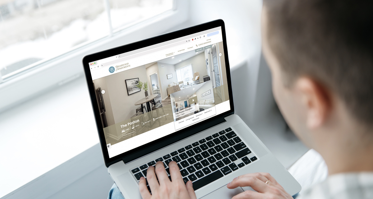 Person using a laptop to view an apartment community’s website showing a floorplan-specific walkthrough video tour. The screen displays “The Paxton” floorplan with high-quality visuals of the living room and other details, illustrating how renters interact with virtual tours during their online apartment search.