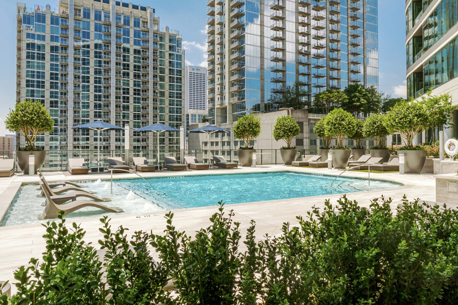 Outdoor pool surrounded by landscaping, with high-rise towers rising behind it.