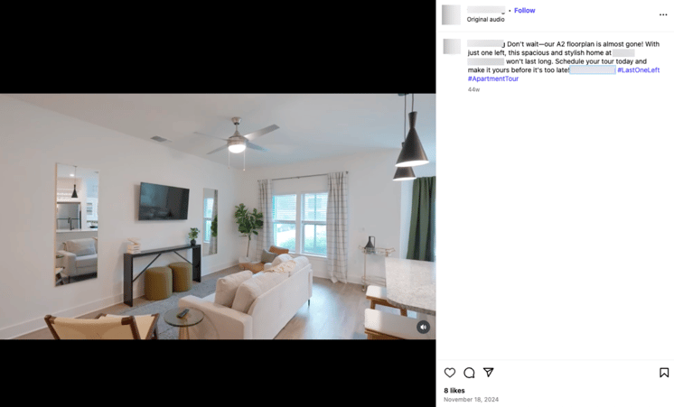 Screenshot of an real Instagram post featuring a bright, modern apartment living room with neutral décor, white walls, wood flooring, and large windows with plaid curtains. A beige sofa faces a mounted TV above a console table, flanked by mirrors and plants. Pendant lights hang above the kitchen counter, creating a spacious and inviting feel.