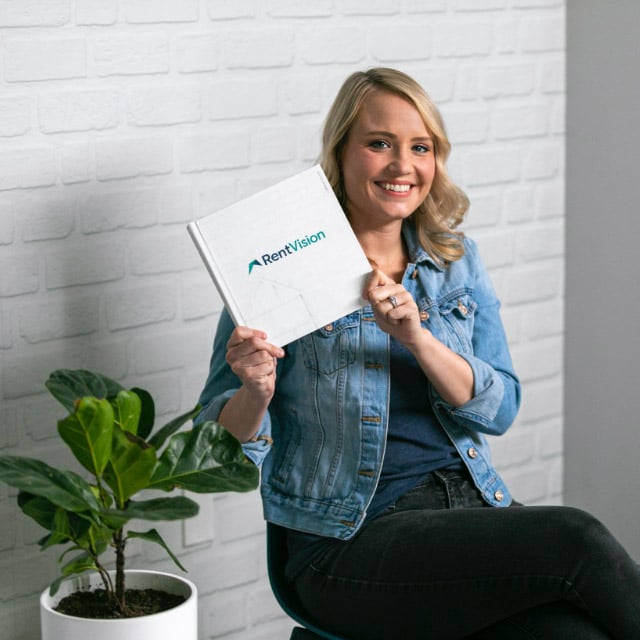 RentVision employee holding a book in front of a white brick wall